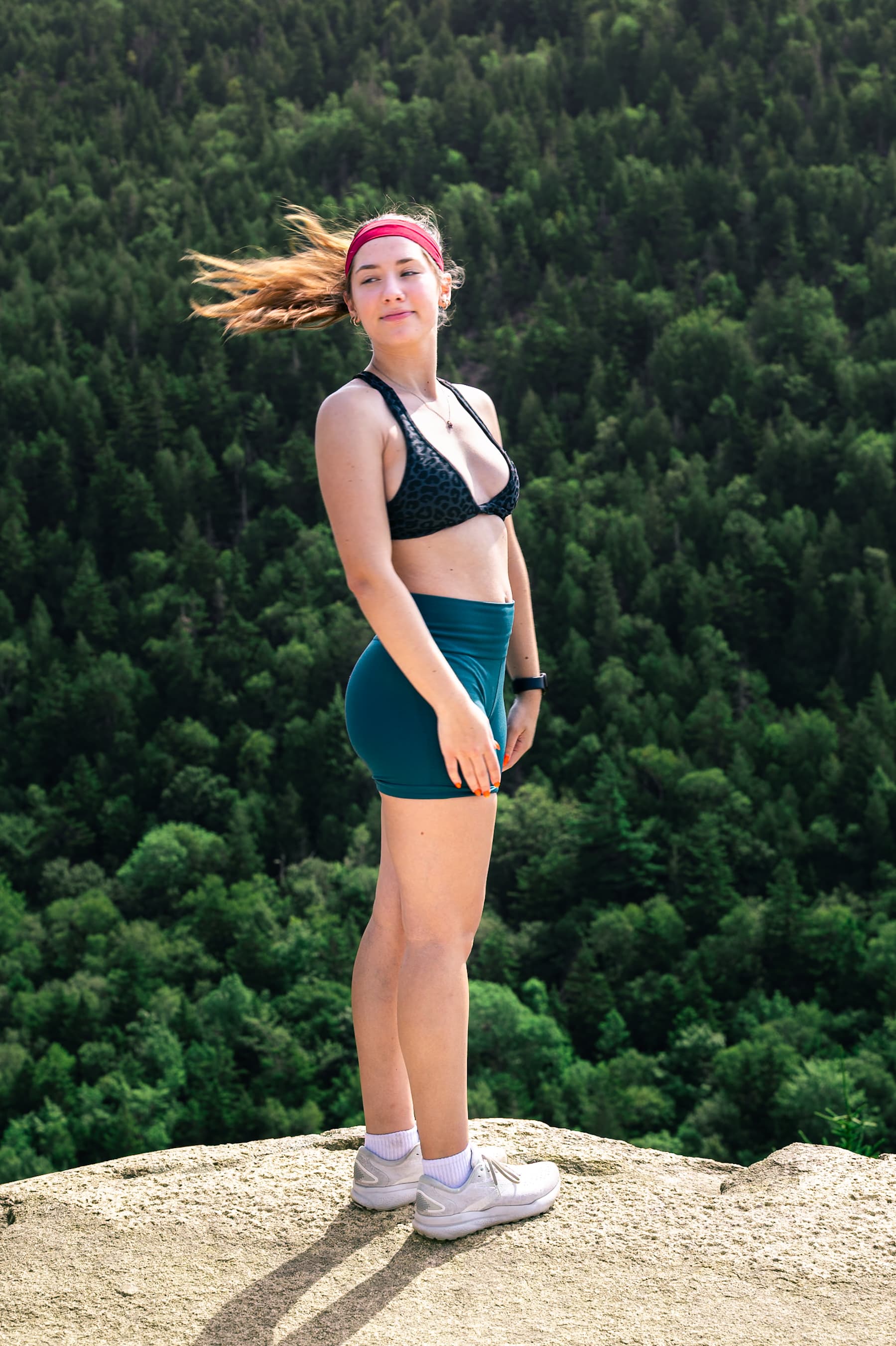 Woman standing on mountain summit with forest view