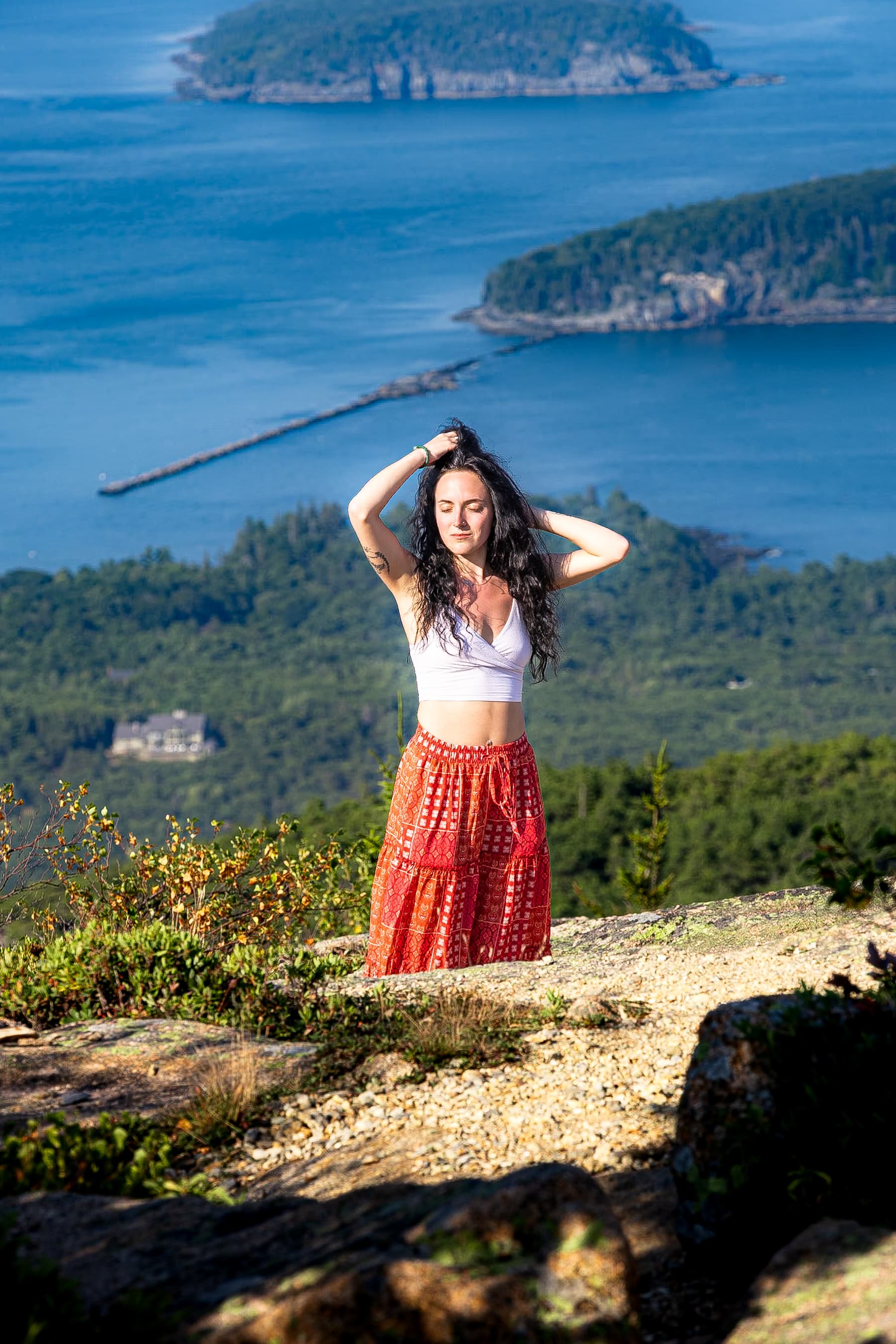 Woman on mountain overlook with ocean and islands