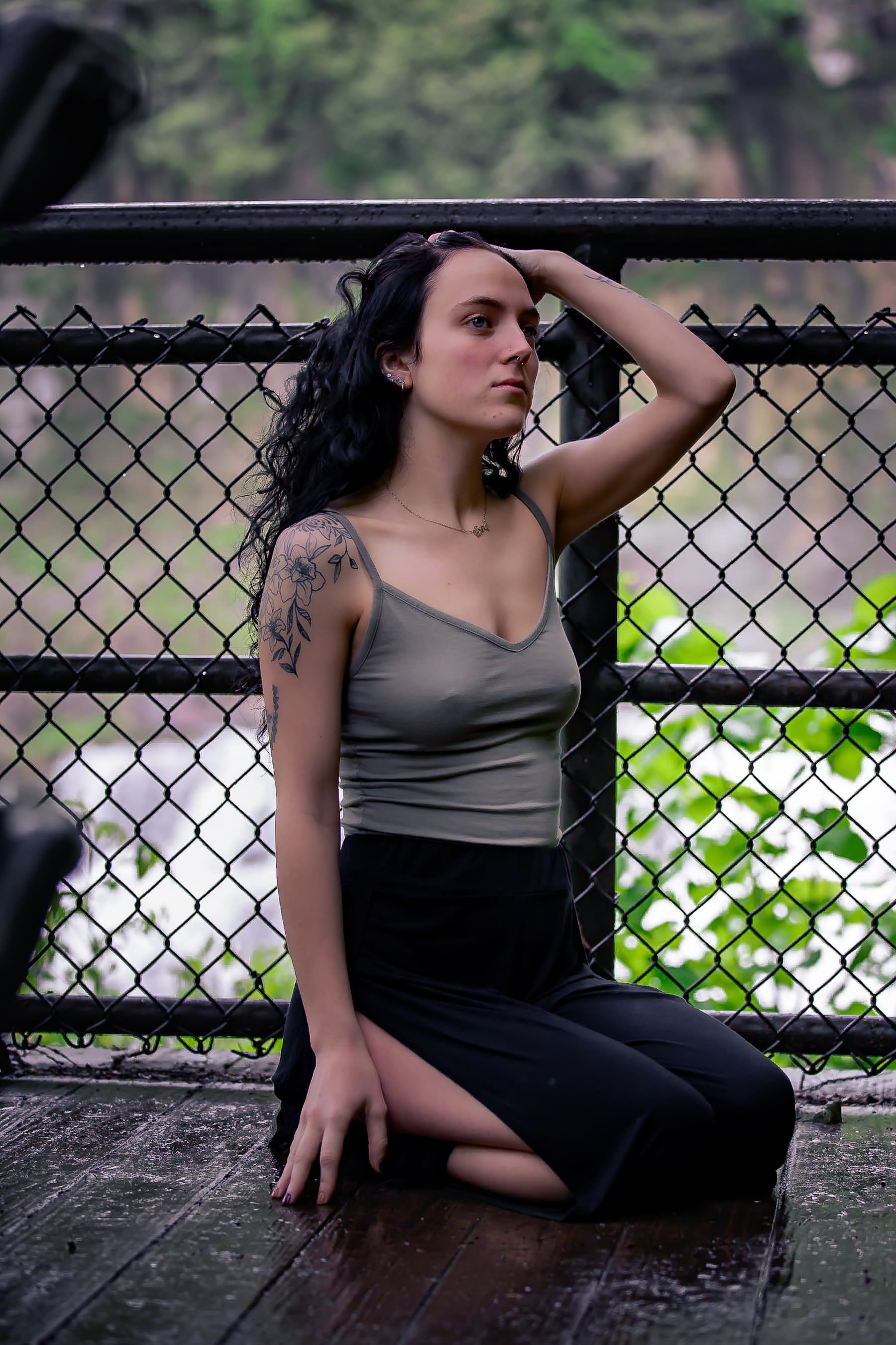 Woman sitting by a fence on a bridge, moody tones
