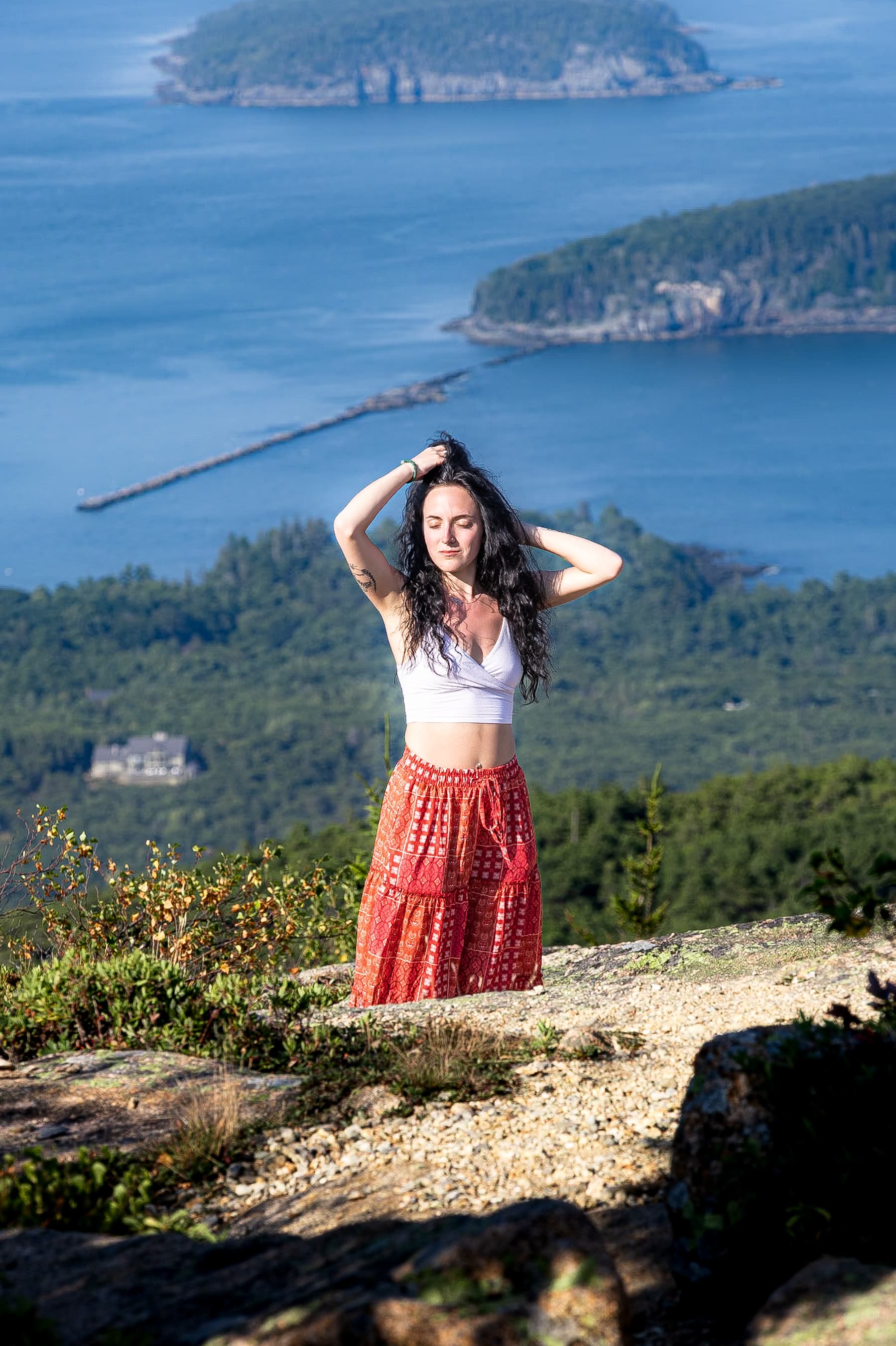 Woman on a granite summit above the harbour, hands in her hair